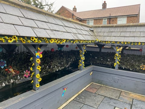 Covered raised pond in Twydall, Gillingham, with a slate roof, sunflower garlands and lanterns, after a maintenance visit
